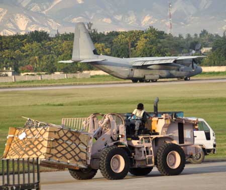 Figure 1 A C-130 Hercules transport lands as Air Force aerial porters move cargo at the airport in Port-au-Prince, Haiti. (Credit Photo: USAF, 1/28/10)