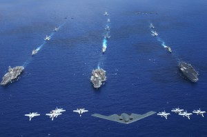 An Air Force B-2 bomber along with other aircrafts from the Air Force, Navy and Marine Corps fly over the Kitty Hawk, Ronald Reagan and Abraham Lincoln Carrier Strike groups during the photo portion of Exercise Valiant Shield 2006. Valiant Shield focuses on integrated joint training among U.S. military forces, enabling real-world proficiency in sustaining joint forces and in detecting, locating, tracking and engaging units at sea, in the air, on land and cyberspace in response to a range of mission areas. Credit: Headquarters USMC, 6/18/06 