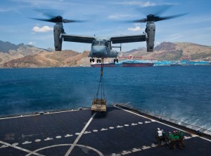 Landing support specialists back away after connecting a Humvee to a U.S. Marine Corps MV-22B Osprey during external lift training at Subic Bay, Philippines, during exercise Freedom Banner 2013. The training was the first time an Osprey has conducted an external lift with the Sacagawea. (U.S. Marine Corps photo by Pfc. Kasey Peacock/Released) 