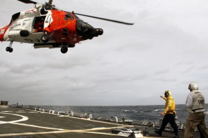 A crew aboard an MH-60 Jayhawk helicopter from Coast Guard Air Station Elizabeth City, N.C., lands aboard the USS Ross, a 505-foot guided missle destroyer, Tuesday, Jan. 14, 2014. The Jayhawk was responding to a disabled sailboat with four people aboard 300 miles east of Cape Henry, Va., and needed the Navy platform to refuel before and after they hoisted the people from the sailboat into the helicopter. U.S. Navy photo