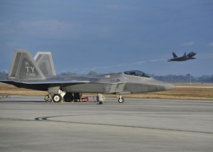 An F-22 Raptor from Tyndall Air Force Base, Fla., sits on the flightline while a Raptor launches from the Tyndall runway Dec. 10, 2015, during Checkered Flag 16-1. The week-and-a-half long exercise focuses on the involvement of the F-22 Raptor, F-35A Lightning II's and legacy aircraft training in a large-force exercise to enhance combat airpower capabilities. (U.S. Air Force photo/Senior Airman Sergio A. Gamboa)