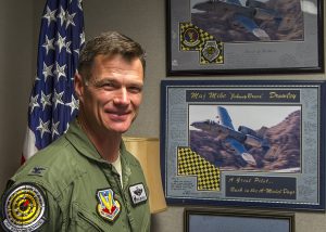 Colonel Michael "Johnny Bravo" Drowley, Commandant of the USAF Weapons School, stands in front of memorabilia recognizing his expertise as A-10 pilot. 